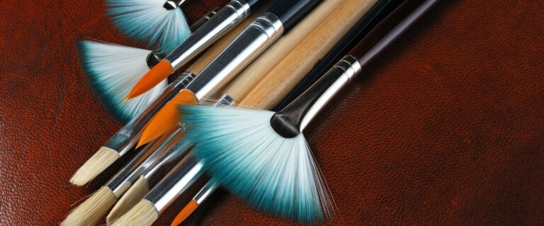 Set of paintbrushes with turquoise bristles on a brown leather-like surface.