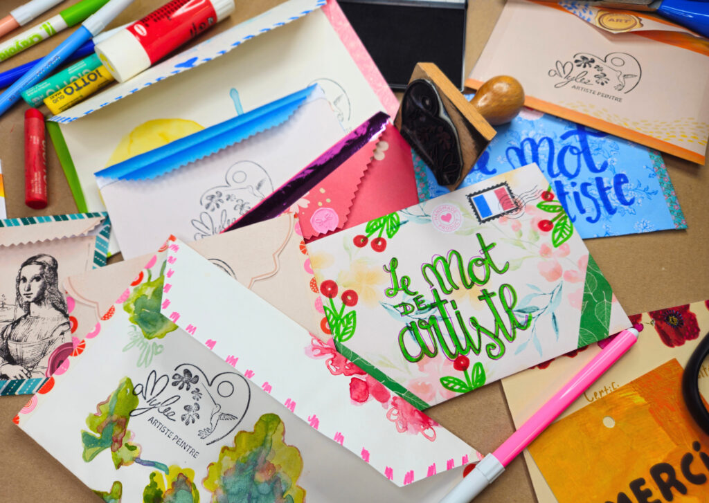 Colorful art supplies scattered on a desk: markers, stamps, painted cards, and scissors.