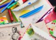 Colorful collage of handmade greeting cards, envelopes, and art supplies scattered on a table when crafting.